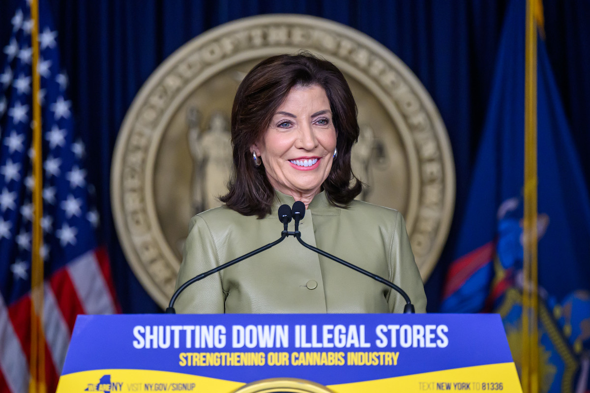 Governor Kathy Hochul standing at a podium that says "shutting down illegal stores"