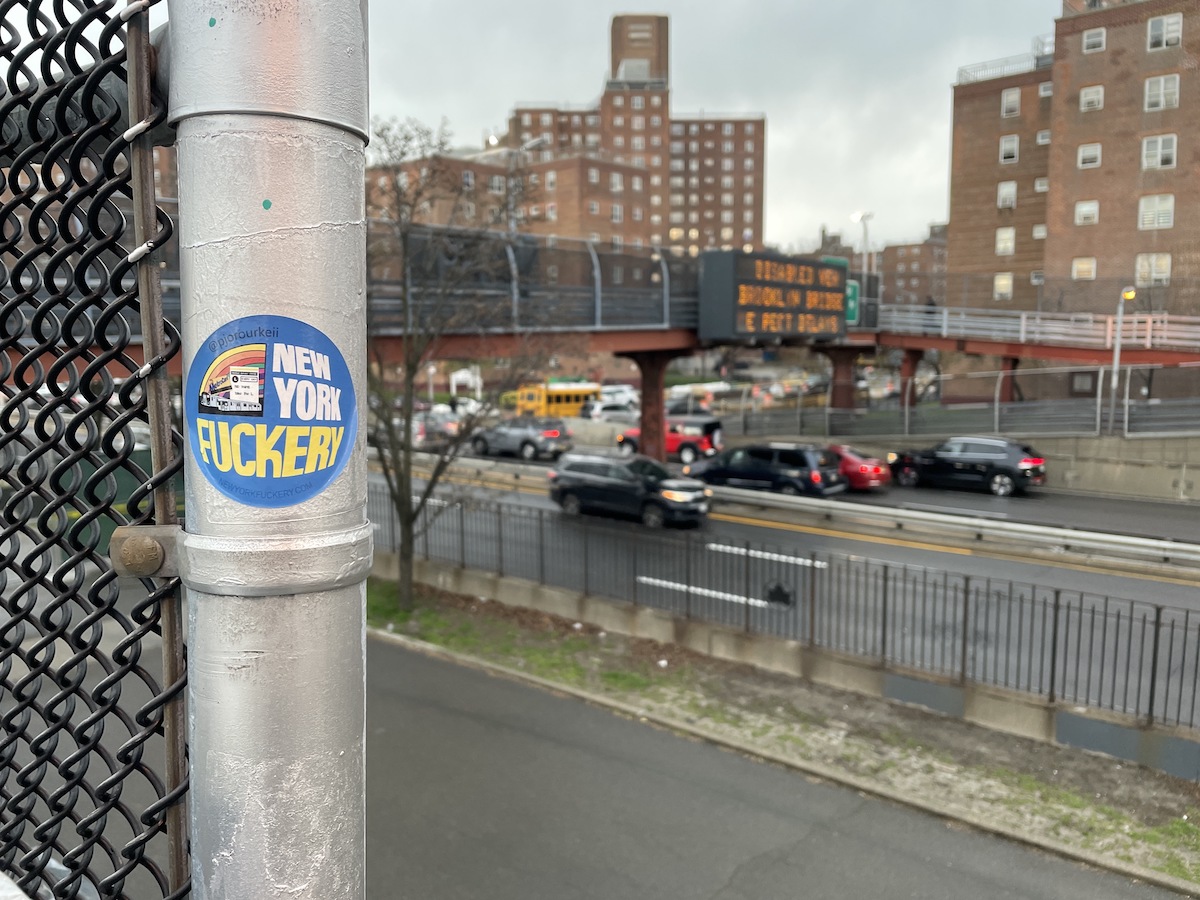 A sticker on a highway overpass that says "New York Fuckery."