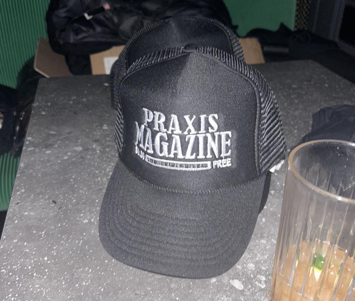 A trucker hat that says "Praxis Magazine"