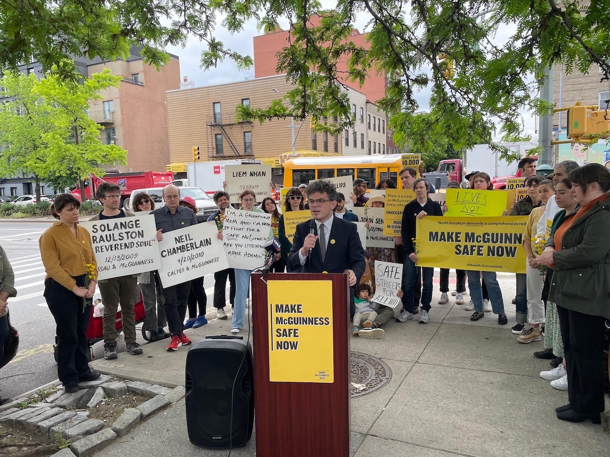 Brooklyn Councilmember Lincoln Rester stands at a podium in front of a group of street safety activists with Make McGuinness Safe next to McGuinness Boulevard.